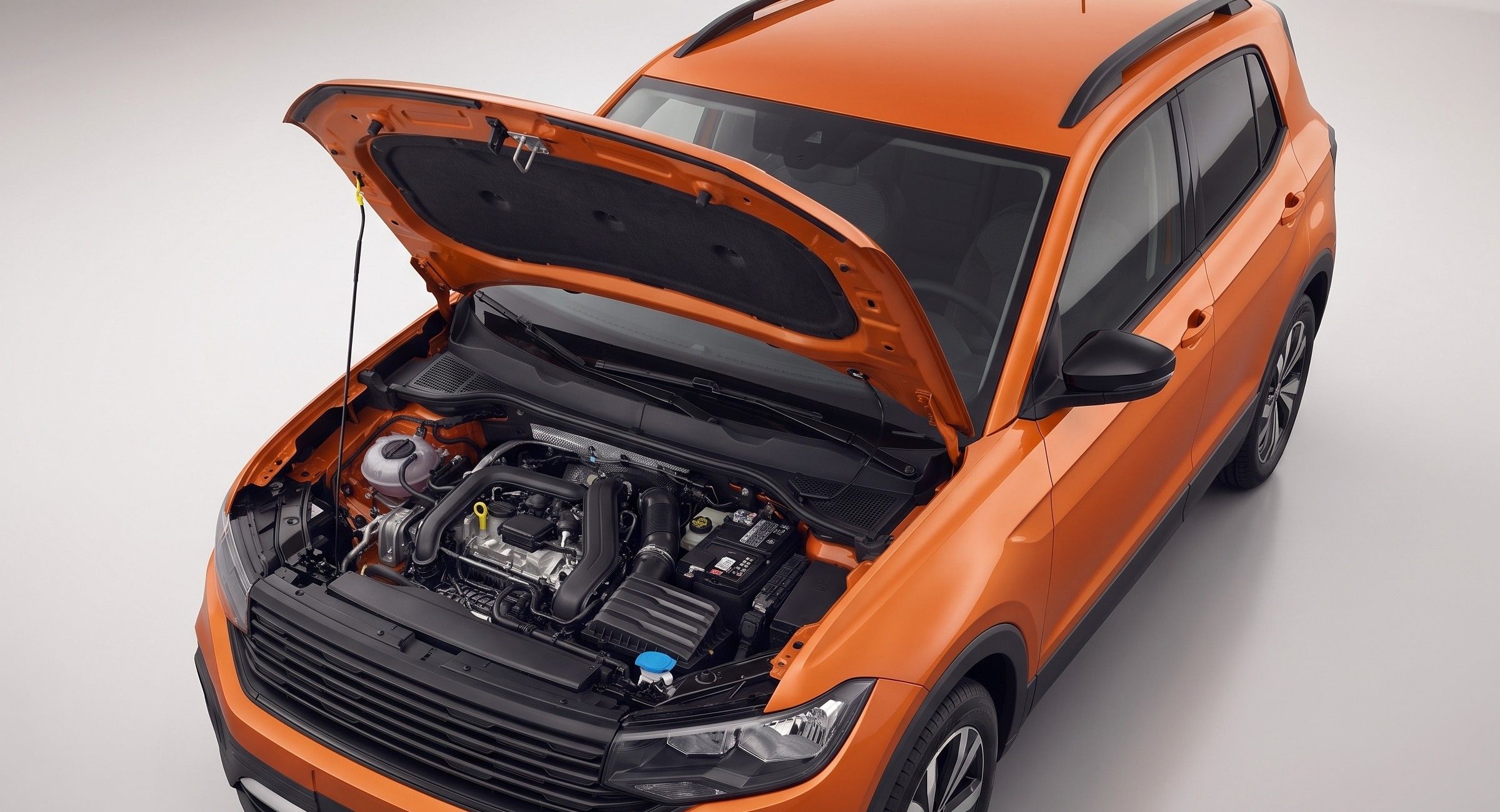 SUV laranja com o capô aberto, mostrando o motor, visto de cima.
